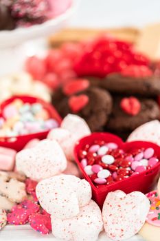 Valentines Day cheese board with a variety of cookies and candies.