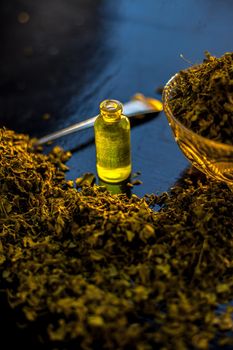 Essential extracted oil of Kasuri Methi or Dried Fenugreek Leaves in a small tiny bottle along with raw dried fenugreek leaves.