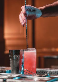 Bartender at nightclub preparing cocktails with bar equipment