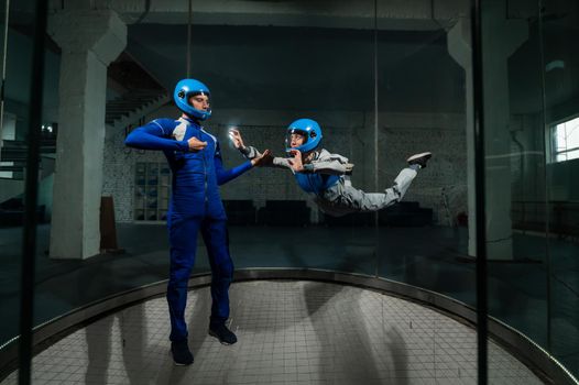 A man teaches a woman how to fly in a wind tunnel. Free fall simulator