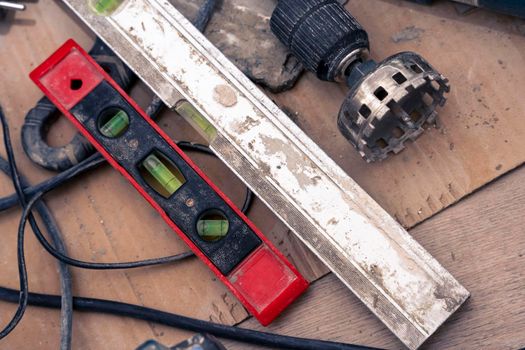 close-up of repair tools. diamond crown for drilling holes in ceramic tiles. close-up of a old bubble construction level lying on a ceramic tile floor during renovation