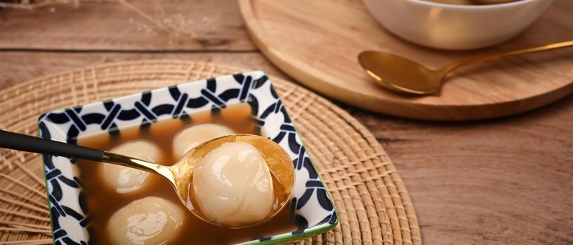 Rice dumpling balls with hot ginger soup in ceramic bowl.