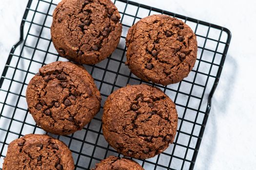 Freshly baked double chocolate chip cookies on a cooling rack.