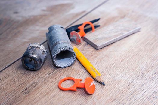 close-up of repair tools. diamond crown for drilling large diameter holes in ceramic tiles, pencil, tile alignment system. Construction tools