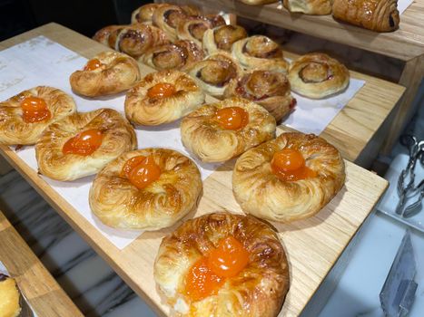 Lines of fresh baked sweet puff pastry stuffed with apricot and peach jelly, super delicious warm fresh buttery sweet puff pastry stuffed with apricot and peach, French and American baked pastries are enjoyed world wide on bakery shop, tasty multiple sweet puff pastry stuffed with apricot and peach