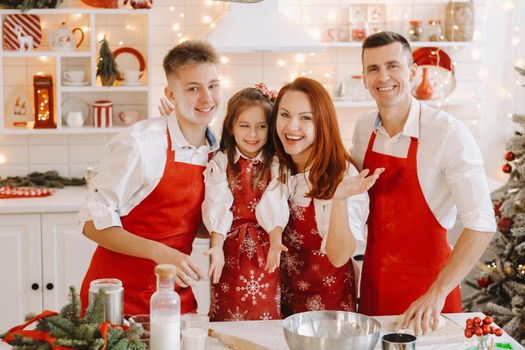 A happy family is standing in the Christmas kitchen and preparing dough for making cookies.