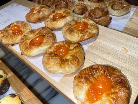 Lines of fresh baked sweet puff pastry stuffed with apricot and peach jelly, super delicious warm fresh buttery sweet puff pastry stuffed with apricot and peach, French and American baked pastries are enjoyed world wide on bakery shop, tasty multiple sweet puff pastry stuffed with apricot and peach