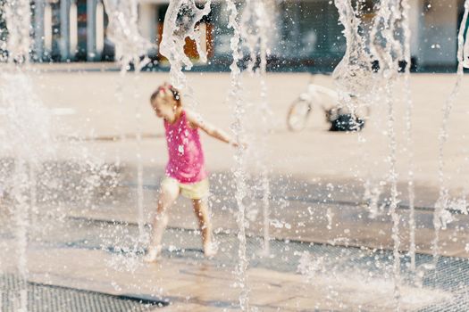a child playing with water in a dry fountain in the city square