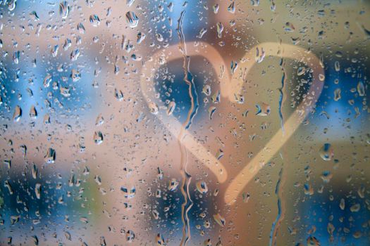 raindrops on the window with a heart pattern - concept photo about love and sadness. High quality photo