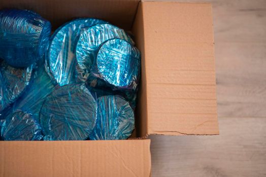 Glassware wrapped with blue wrapping nylon at the bottom of a cardboard box. High quality photo