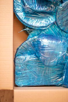 Glassware wrapped with blue wrapping nylon at the bottom of a cardboard box. High quality photo