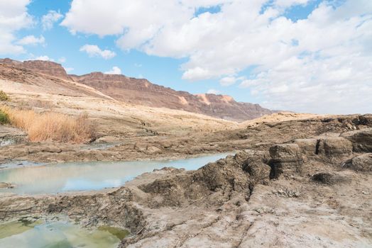 Sinkhole filled with turquoise water, near Dead Sea coastline. Hole formed when underground salt is dissolved by freshwater intrusion, due to continuing sea-level drop. . High quality photo