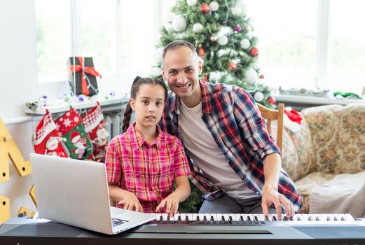 Smiling family on Christmas morning play music on piano