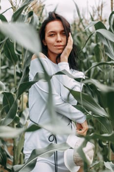 A brunette girl in a white dress in a cornfield. The concept of harvesting.