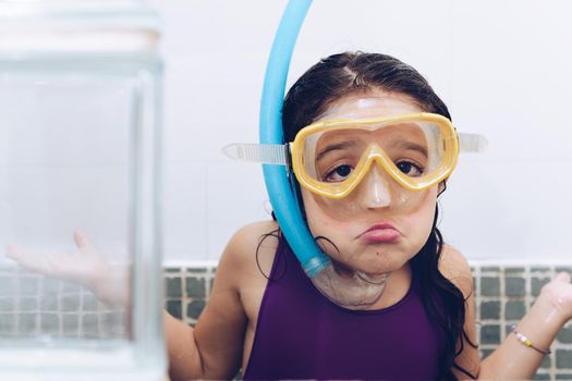 portrait of a funny pretty little girl grimacing with snorkel goggles in the tub while taking a bath in the bathtub, kids hygiene concept, copy space for text