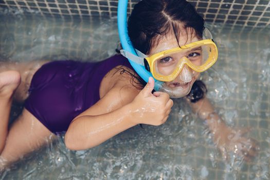 portrait of a beautiful little girl having fun swimming with snorkel goggles in the tub while taking a bath in the bathtub, kids hygiene concept