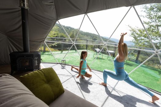 Mother and daughter doing exercise indoors.