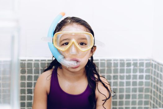 portrait of a happy pretty little girl with snorkel goggles in the tub while taking a bath in the bathtub, kids hygiene concept, copy space for text