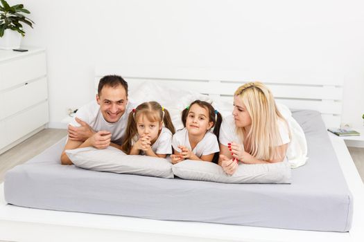 Young family resting together in parent's bed.