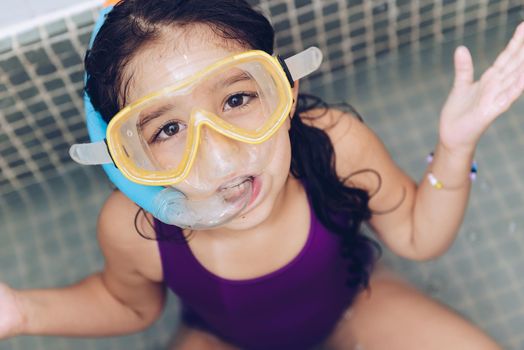 portrait of a funny pretty little girl with snorkel goggles in the tub while taking a bath in the bathtub, kids hygiene concept
