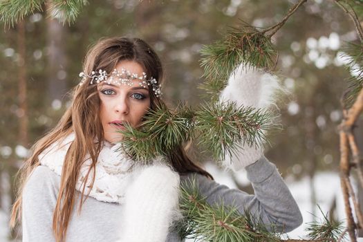 Beautiful bride in a white dress with a bouquet in a snow-covered winter forest. Portrait of the bride in nature.