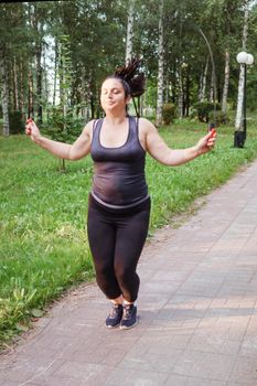 A charming brunette woman plus-size body positive practices sports in nature.