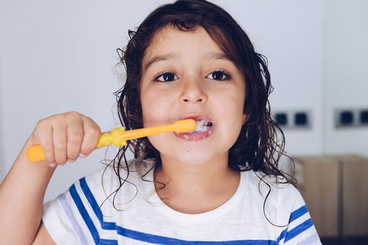 portrait of a little girl brushing her teeth in the bathroom before going to bed after taking a shower, kids hygiene concept