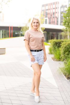 Portrait of young beautiful smiling hipster woman in trendy summer shorts. Sexy carefree model posing on the street background.