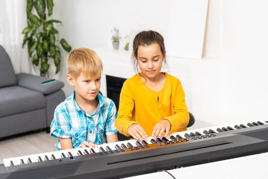 Brother and sister play the synthesizer. Children play at piano. family games.
