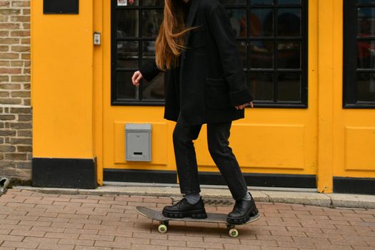A girl near yellow wall with a skateboard