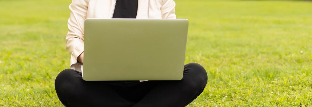 Young woman using laptop in the park.