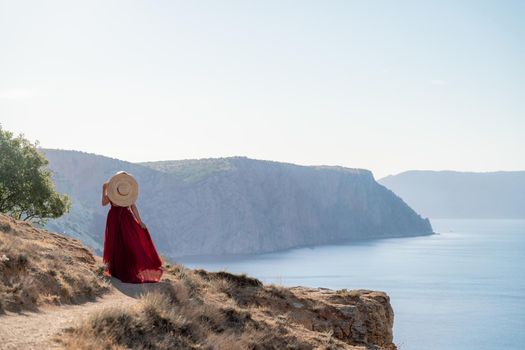 A woman in a red flying dress fluttering in the wind, against the backdrop of the sea