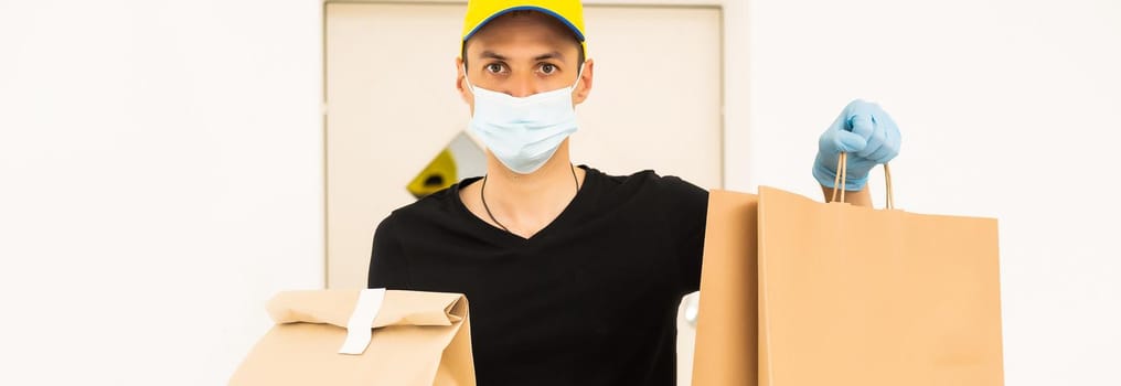 Delivery man holding cardboard boxes in medical rubber gloves and mask. copy space. Fast and free Delivery. Online shopping and Express delivery. Quarantine.