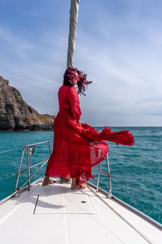 Attractive middle-aged woman in a red dress on a yacht on a summer day. Luxury summer adventure, outdoor activities