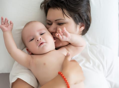 happy mother with baby on bed.