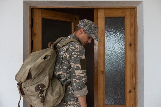 military man with a backpack goes out the door.