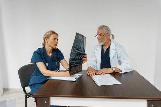 Team of doctors looking on results of X-Ray or MRI scan of patient's spine in medicine office