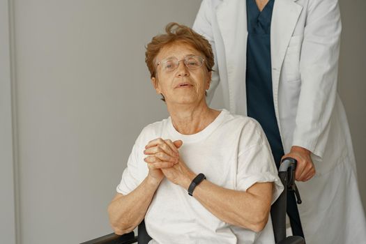 Professional male doctor carrying patient on wheelchair in medicine clinic hall. High quality photo