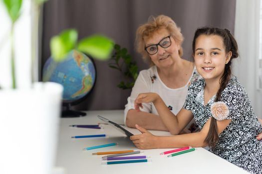Cute little girl with her grandmother looking at tablet at home.