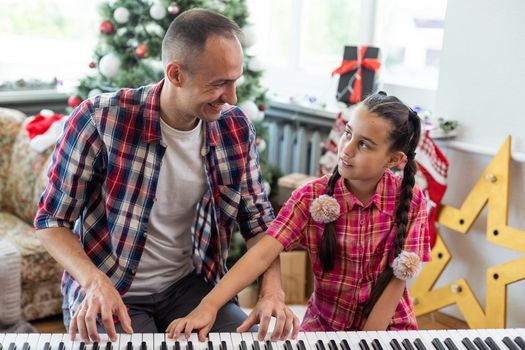 Smiling family on Christmas morning play music on piano