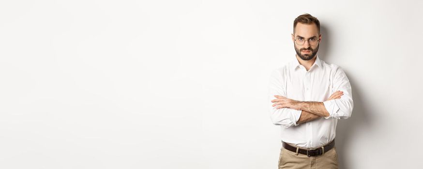 Angry manager looking disappointed, cross arms on chest and frowning displeased, standing over white background. Copy space