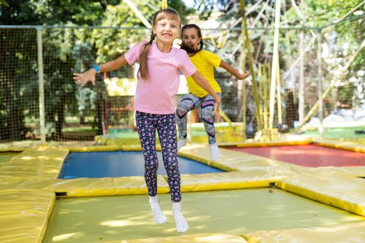 two girls jumping on a trampoline on a summer day