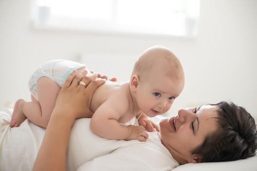 happy mother with baby on bed.