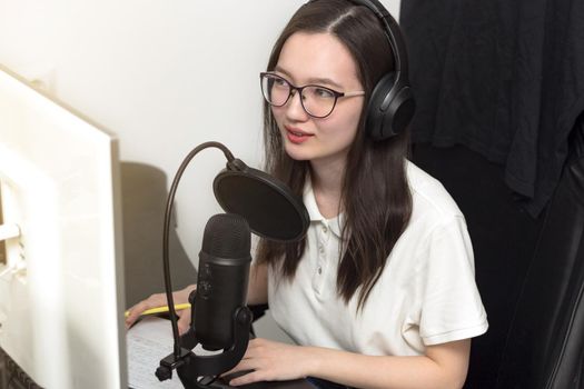 Young woman with glasses, microphone and headphones recording podcast at studio, professional record audio, technology and media concept