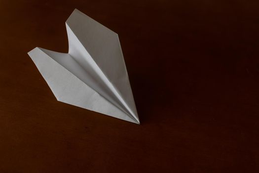 White paper plane on brown background, travel and holiday concept