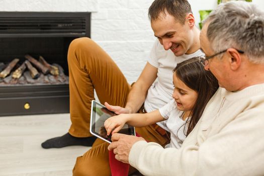 Smiling family with grandparents holding photo album at home.