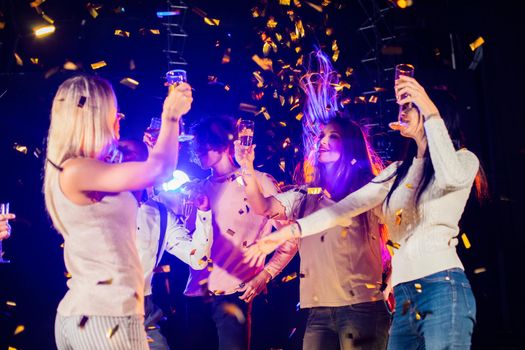 Group of friends dancing in nightclub celebrating with champagne