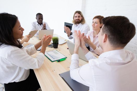 Group of business people applauding sitting at the negotiating table