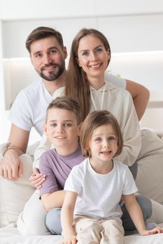 Happy family of parents with children sitting together on sofa at home