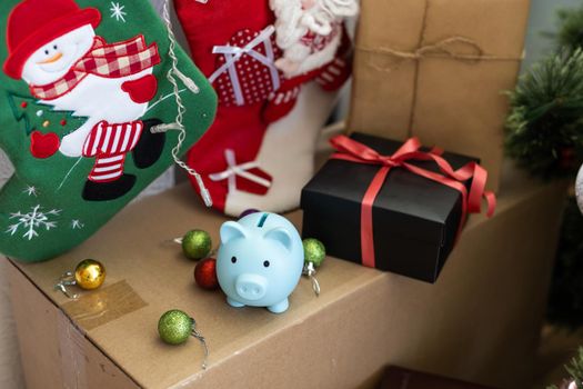 A small ceramic piggy bank with a Christmas tree. In the background of a New Year's gifts. Symbol of the new year 2023. Christmas card